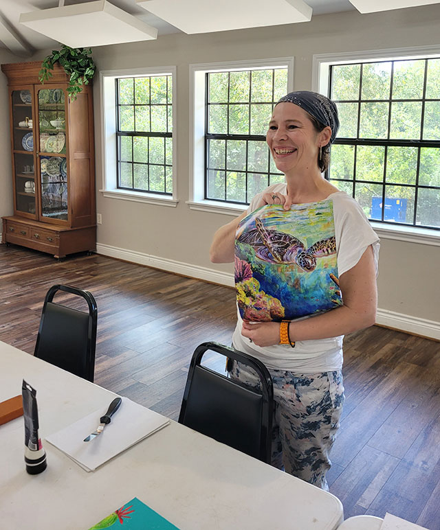 Photo of Virginia holding up a print of a recent painting using the technique.